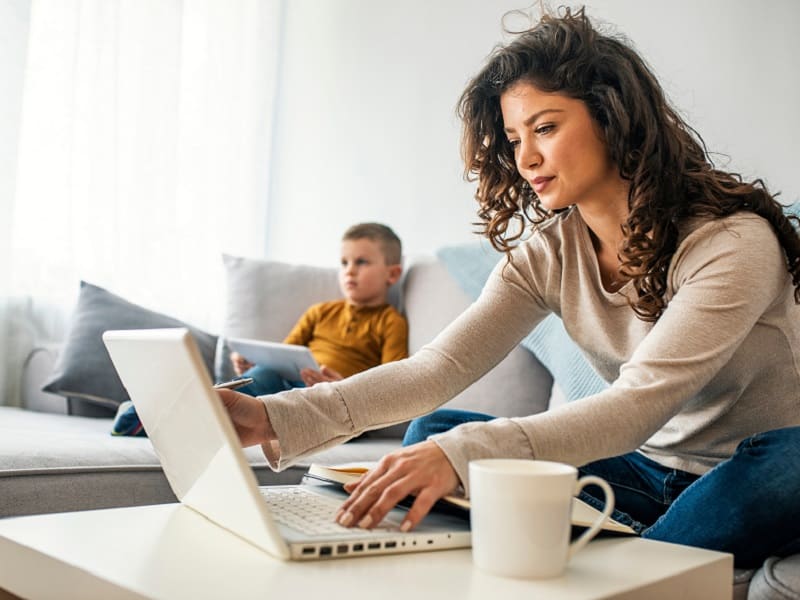 woman on laptop with child in background